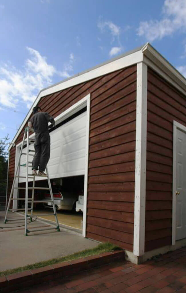 ガレージの経年劣化した壁面をDIYで塗装している写真