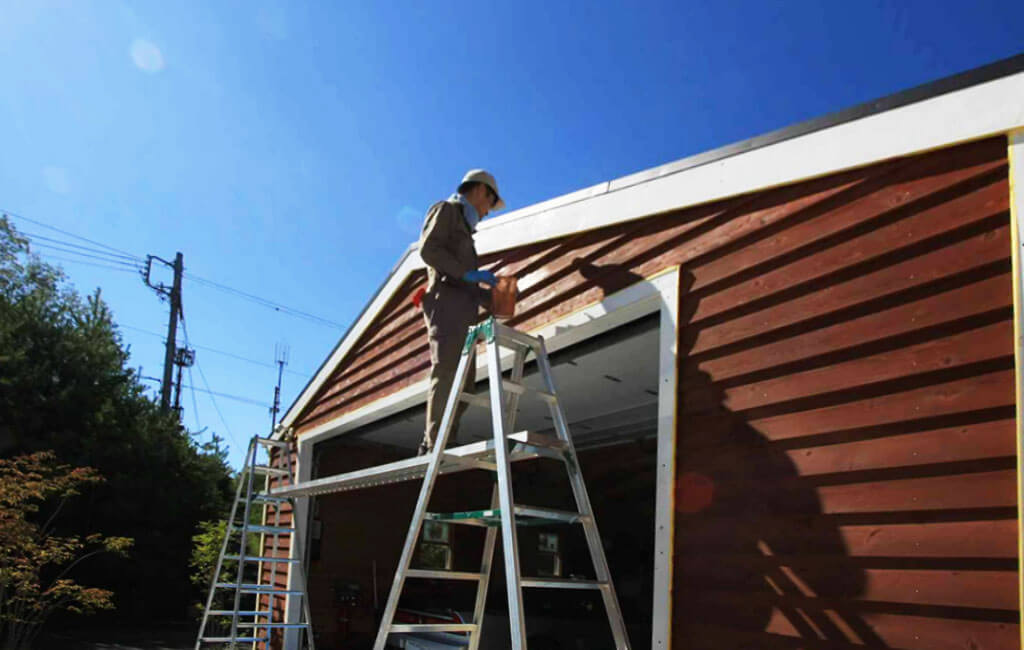 経年劣化したガレージの壁面をDIYで塗装している写真